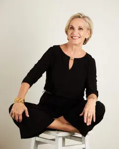 A woman sitting on top of a white stool.