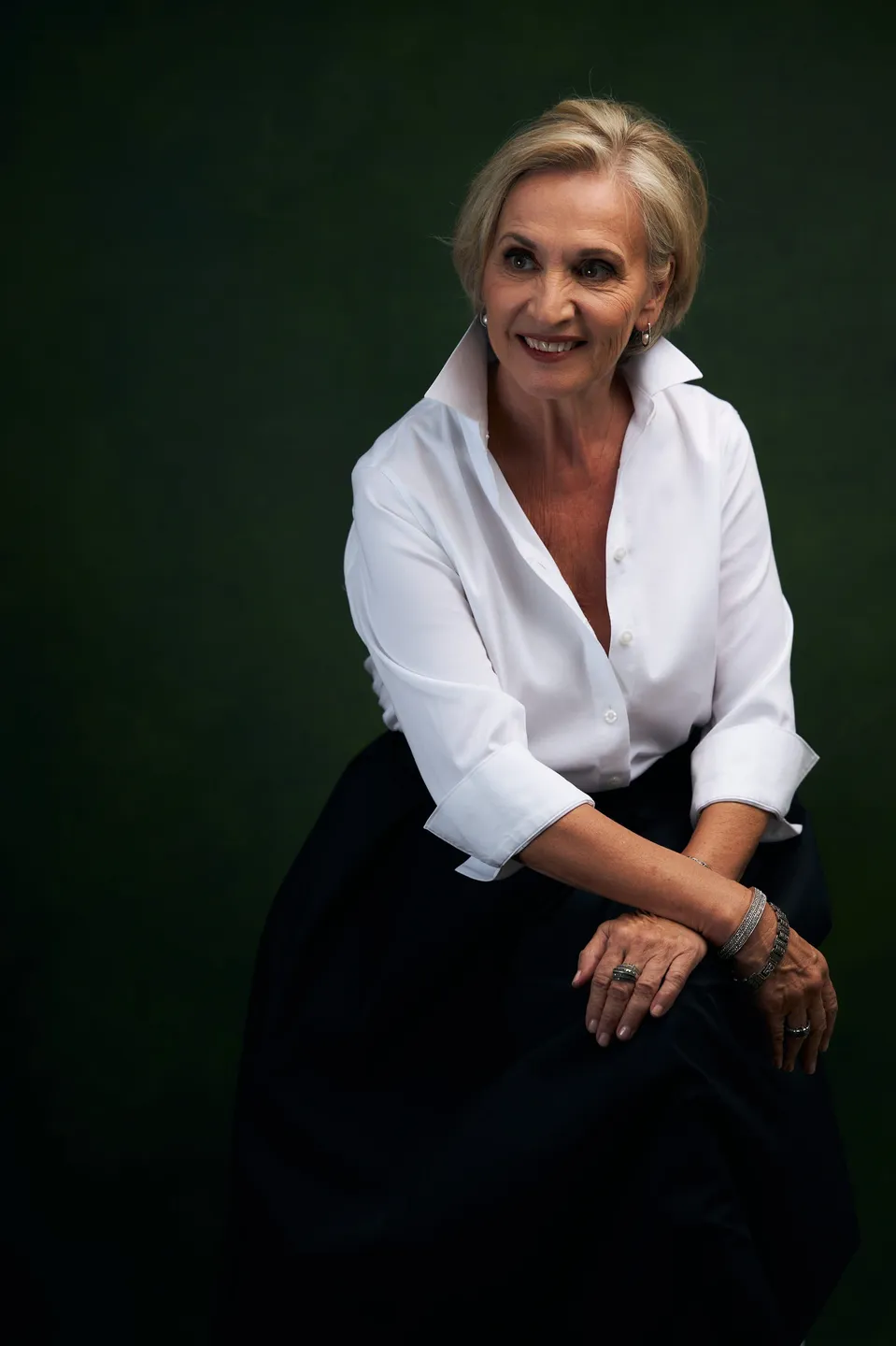 A woman sitting on top of a chair in front of a green wall.